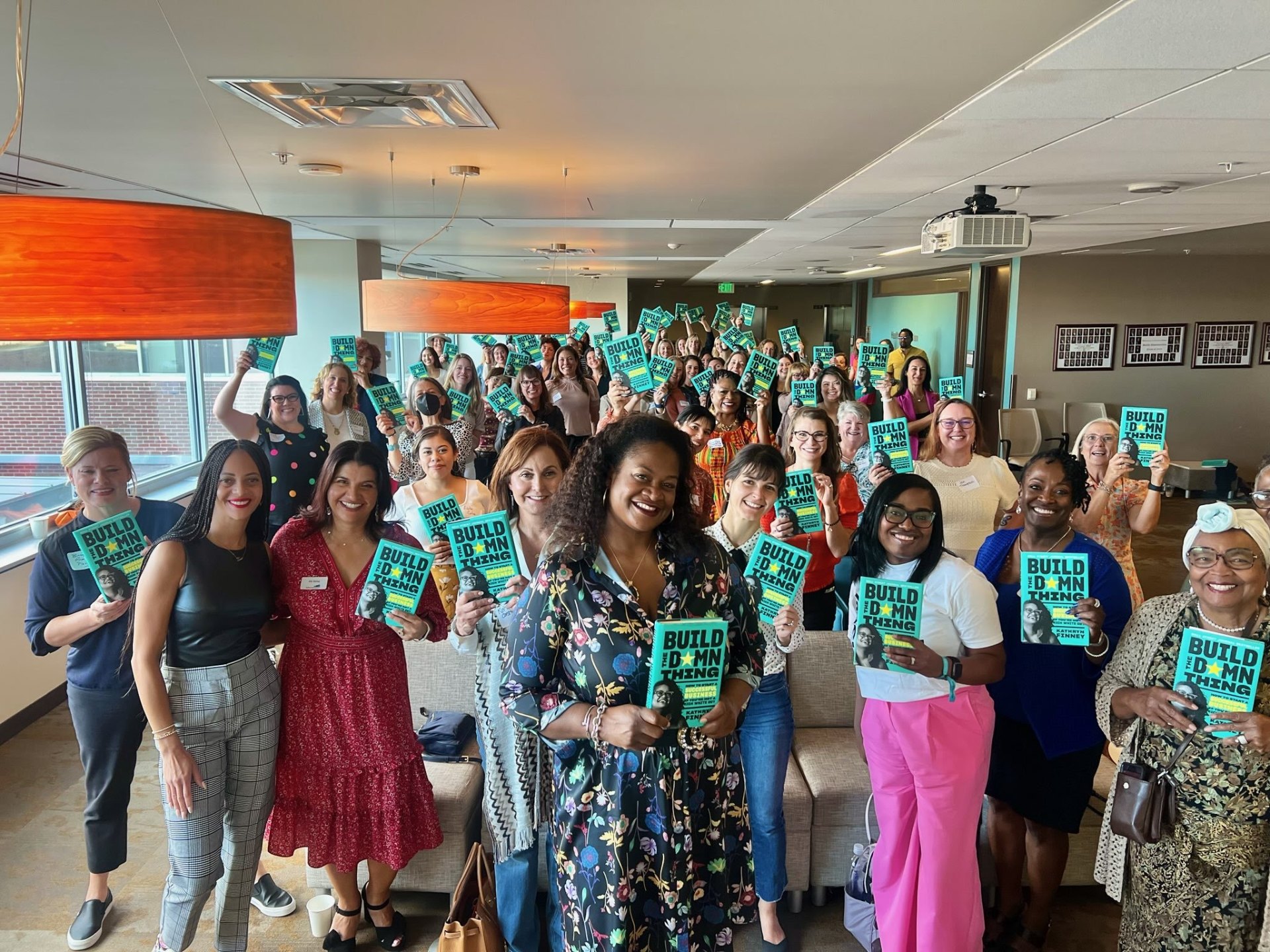 Group of Black women entrepreneurs gathered together holding copies of Build the Damn Thing, representing the community supported by the Doonie Fund